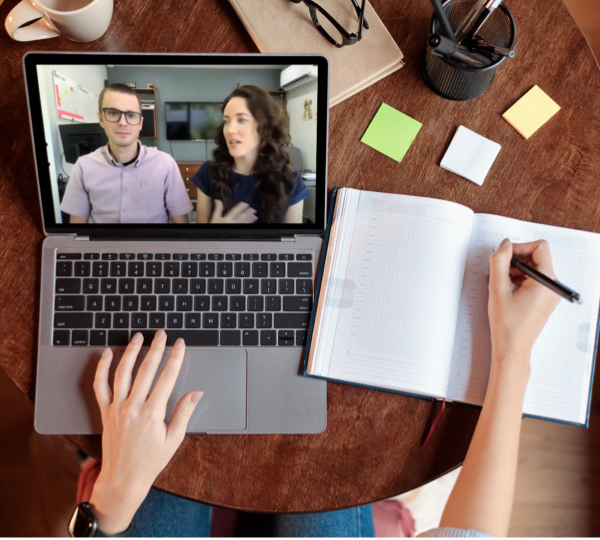 Angela and Cris on a virtual meeting shown in a laptop someone is working on and taking notes